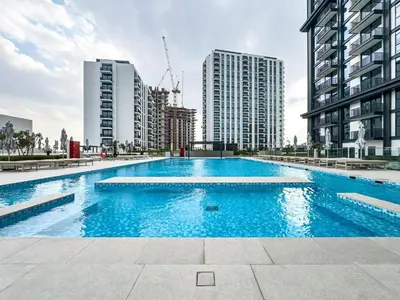 a large swimming pool in a city with tall buildings at Superhost - 1BR Apartment , Pool & Gym , Near Dubai Hills Mall in Dubai