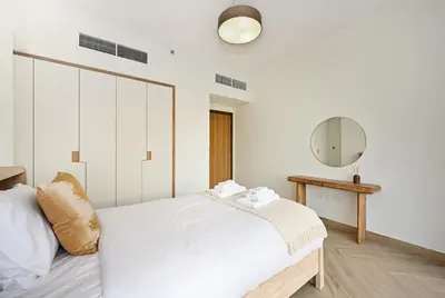 a white bedroom with a bed and a mirror at Bloomfields Luxurious 3BR in West Residences in Dubai