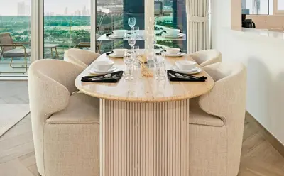 a dining room table with chairs and a table with glasses at Bloomfields Luxurious 3BR in West Residences in Dubai