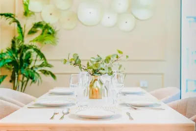 a table with plates and glasses and a vase with flowers at TRPS - Act Towers, Downtown Dubai - Full Burj Khalifa View, High-End 3BR plus Maids in Dubai