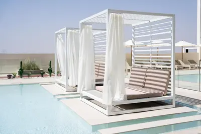 a swimming pool with two lounge chairs and a pavilion at Binghatti Azure Minimal Luxe Studio with Pool & Gym in Dubai