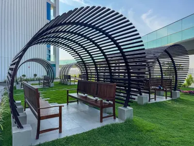 a group of benches sitting under an arch in a park at Modern Studio Near Miracle Garden & Dubai Hills in Dubai