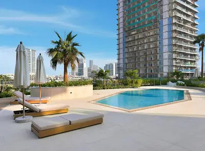 a swimming pool with chairs and umbrellas and a building at New Luxury 1BR with Private Pool & Balcony in JVC in Dubai