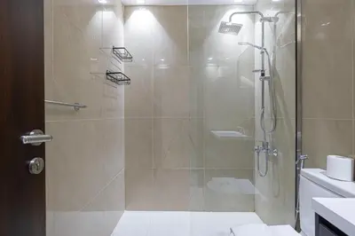 a bathroom with a shower with a glass door at Stylish 1BR Apartment Near Silicon Mall & Airport in Dubai