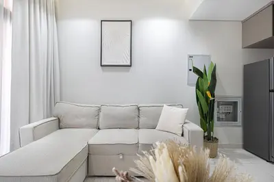a white living room with a couch and a picture at Stylish 1BR Apartment Near Silicon Mall & Airport in Dubai