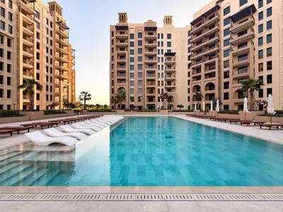a large swimming pool with chairs and buildings at GuestReady - 1 BHK | Serene 9th-Floor Escape in Dubai