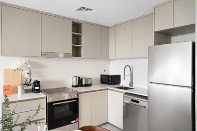 a kitchen with white cabinets and a stainless steel refrigerator at GuestReady - 1 BHK | Serene 9th-Floor Escape in Dubai