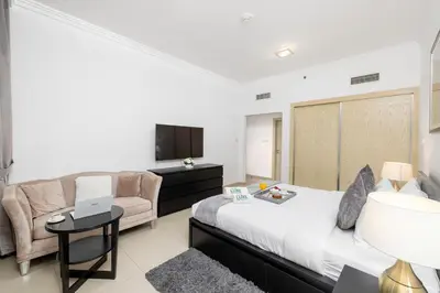 a bedroom with a bed and a couch and a tv at JBR Al Bateen Residences By Luxe Living Collection - Private Beach and Sea Views in Dubai