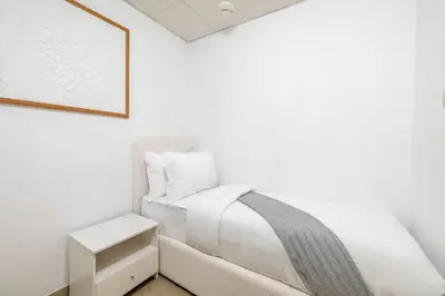 a white bedroom with a bed and a table at JBR Al Bateen Residences By Luxe Living Collection - Private Beach and Sea Views in Dubai