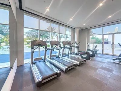 a gym with a row of treadmills in a room with windows at JBR Al Bateen Residences By Luxe Living Collection - Private Beach and Sea Views in Dubai