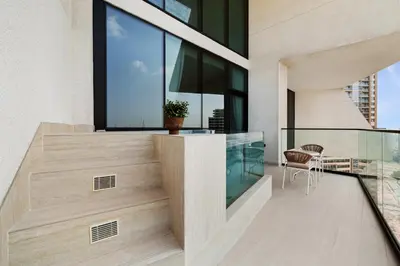 a balcony with a table and chair on a building at New 1BR Urban Oasis with Pools & City Views in JVC in Dubai