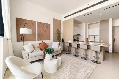 a living room with white furniture and a kitchen at New 1BR Urban Oasis with Pools & City Views in JVC in Dubai