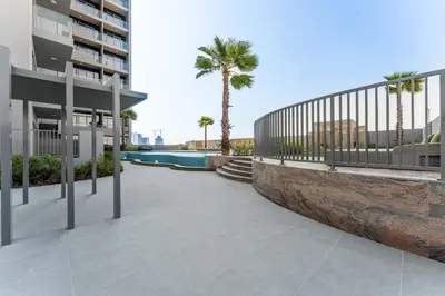 a walkway next to a building with palm trees at Brand New 1BDR with Pool, Jacuzzi, Sauna, Gym in Dubai