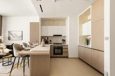 a kitchen with white cabinets and a kitchen island with chairs at New Chic 1BR Apt with Private Pool & City View in JVC in Dubai