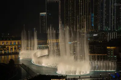 a water fountain in the middle of a city at night at GRaNDE 2BR Best BURJ Khalifa & Fountain, Next to DXB Mall in Dubai