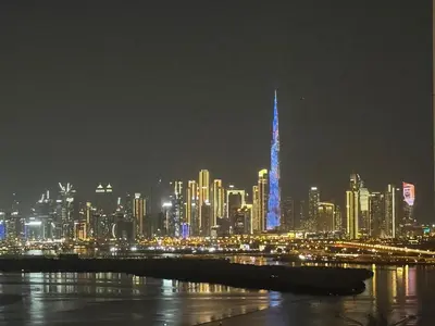 a city skyline at night with a blue lit up building at 1-Bedroom Apartment - Burj Khalifa -Water View in Dubai