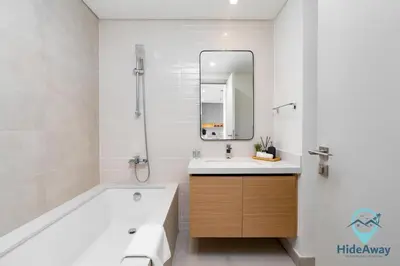 a bathroom with a tub and a sink and a mirror at Stunning 1BR l Creek Crescent Suite in Dubai