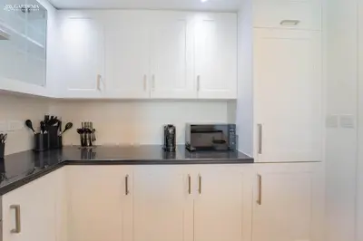 a white kitchen with white cabinets and a microwave at 29 Boulevard-Burj Khalifa View-Downtown Dubai-Lit Apartment in Dubai