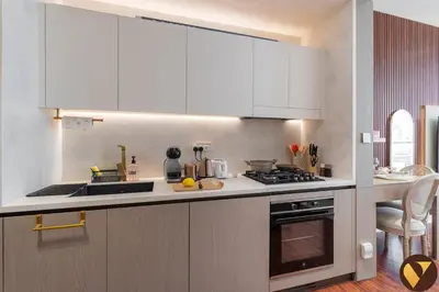 a kitchen with white cabinets and a stove top oven at Vogue JVC Binghatti Phoenix near Circle Mall, Studio Apartment with Balcony and Access to all Amenities in Dubai