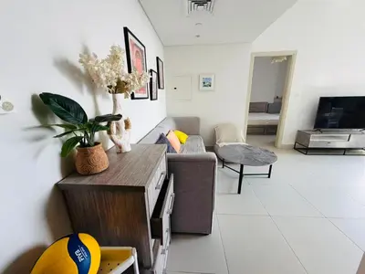a living room with a couch and a television at 1BR, Afnan 2, Midtown, Dubai Production City in Dubai