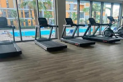 a gym with several treadmills and a pool at 1BR, Afnan 2, Midtown, Dubai Production City in Dubai