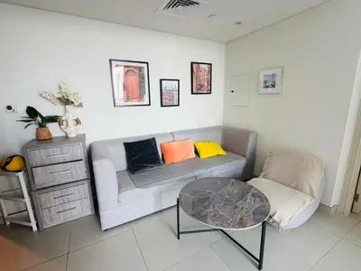a living room with a couch and a table at 1BR, Afnan 2, Midtown, Dubai Production City in Dubai