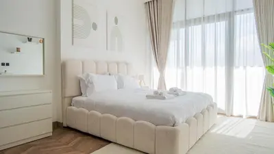 a white bedroom with a large bed with two towels on it at Stunning Burj Khalifa View Luxury 2BR Business Bay in Dubai