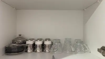 a shelf with glass bottles and plates on it at Luxury Studio big Balcony in Dubai
