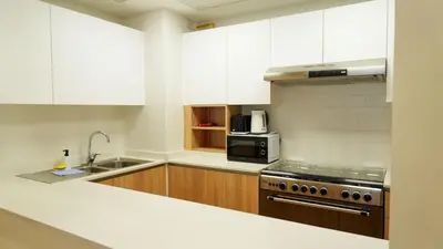 a kitchen with white cabinets and a sink and a stove at Stunning 2BR Canal & Burj Khalifa Partial View 4 in Dubai