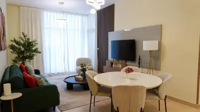 a living room with a couch and a table with chairs at Stunning 2BR Canal & Burj Khalifa Partial View 4 in Dubai