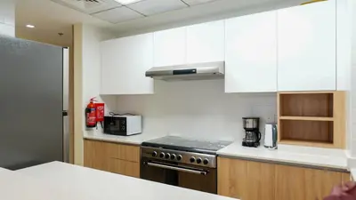a kitchen with white cabinets and a stove top oven at Stunning 2BR Canal & City Skyline View 7 in Dubai