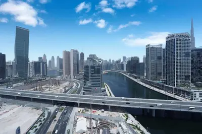 a city with a bridge over a river with traffic at Elegant 2BR Canal & Burj Khalifa Partial View 5 in Dubai