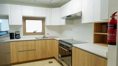 a kitchen with white cabinets and a sink and a stove at Elegant 2BR Canal & Burj Khalifa Partial View 5 in Dubai