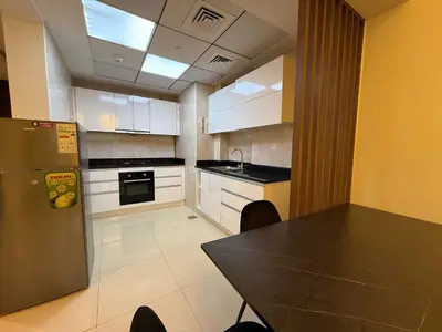 a kitchen with a table and a refrigerator at Comfort Focused 1BR Laya JVC in Dubai