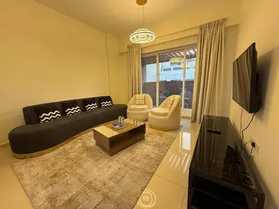 a living room with a black couch and a tv at Comfort Focused 1BR Laya JVC in Dubai