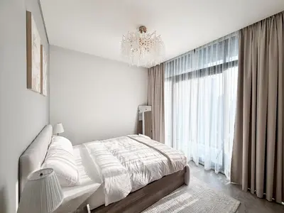 a white bedroom with a bed and a chandelier at 1BR - Peninsula One in Dubai