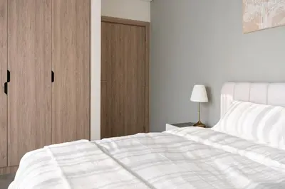a bedroom with a white bed and a wooden door at 1BR - Peninsula One in Dubai