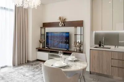 a living room with a table and chairs and a tv at 1BR - Peninsula One in Dubai