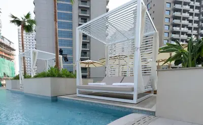 a whitevisorvisor chair sitting next to a swimming pool at Premium 1BR W Private Pool Binghatti Royale in Dubai