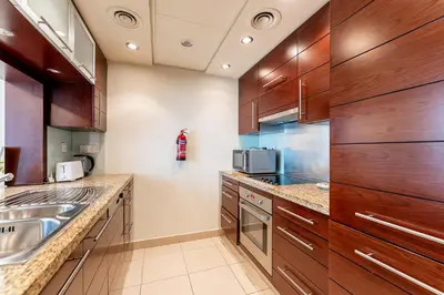 a kitchen with wooden cabinets and a sink at HAVN - 1 Bedroom in Downtown Dubai in Dubai