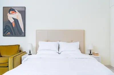 a bedroom with a white bed and a yellow chair at Nasma Luxury stays - Executive stay with hotel facilities in Dubai