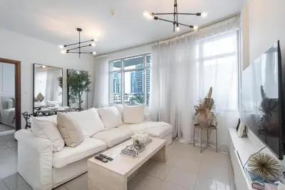 a living room with a white couch and a table at Bright, modern flat on the Marina Promenade in Dubai
