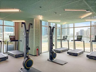 a gym with treadmills and ellipticals in a building at VayK - Luxury 1 BD with Panoramic Canal Views in Dubai