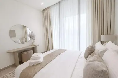 a white bedroom with a bed and a mirror at Serene 1BR Retreat W Private Pool Binghatti Royale in Dubai
