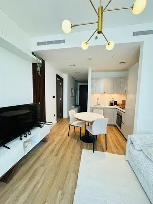 a living room with a table and a kitchen at Superb 1BR high floor apartment on Sobha Hartland in Dubai