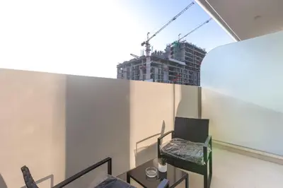 a balcony with a chair and a building at Elegant Designer Studio with Balcony & Rooftop Pool in JVC in Dubai