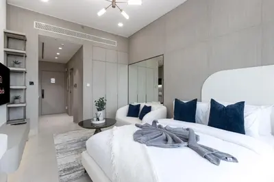 a bedroom with two white beds and blue pillows at Elegant Designer Studio with Balcony & Rooftop Pool in JVC in Dubai