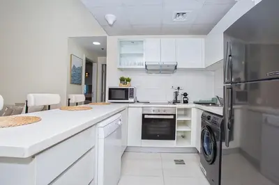 a kitchen with white cabinets and a stainless steel refrigerator at Stunning 2 Bedroom Apartment in JBR with Balcony in Dubai