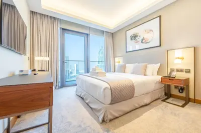 a bedroom with a bed and a desk and a window at 3br on the 49th floor of Address Opera in Dubai