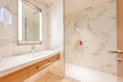 a bathroom with a shower and a sink and a mirror at 3br on the 49th floor of Address Opera in Dubai